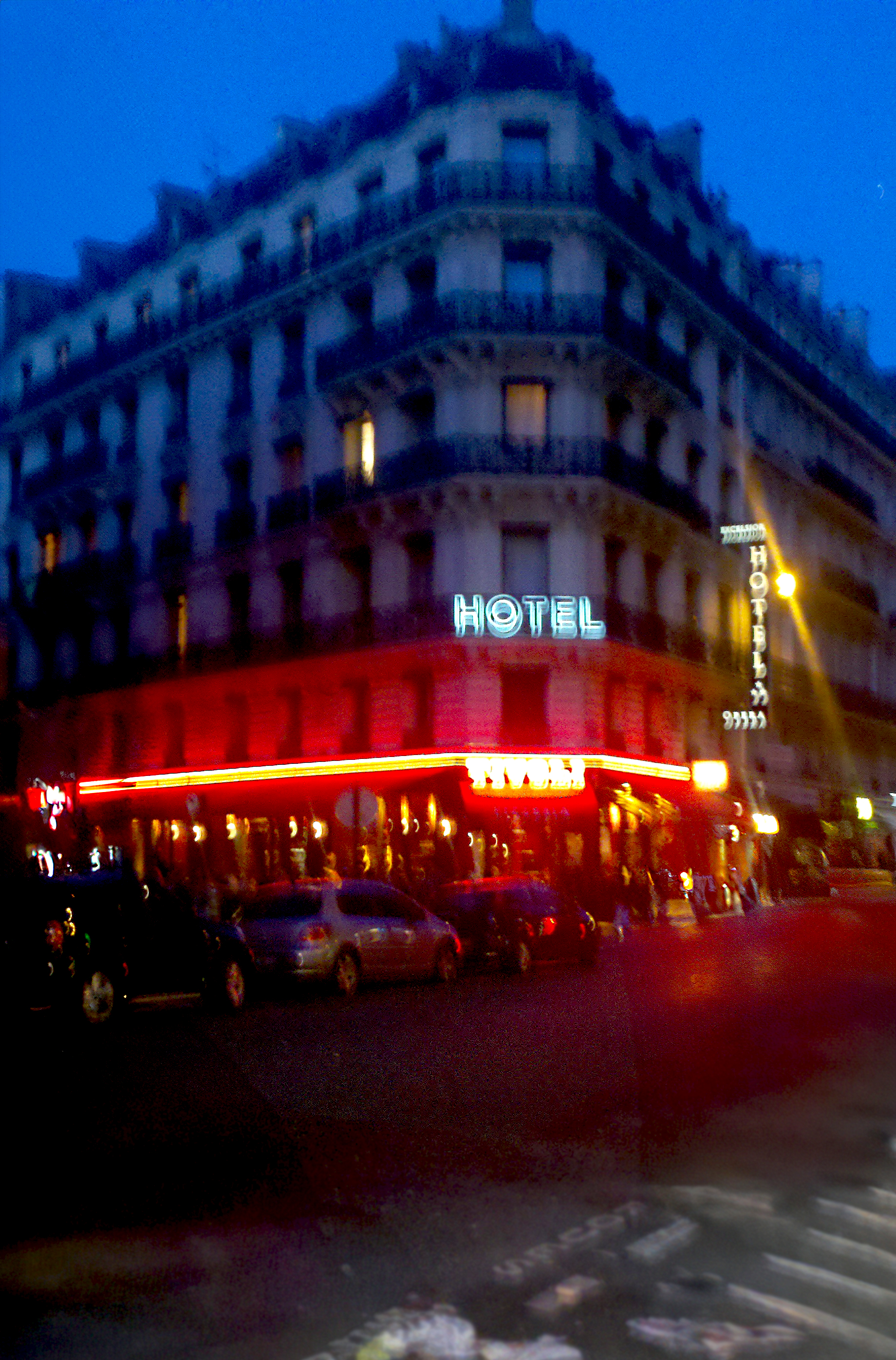 Historic corner hotel glowing with neon on a rain-darkened city street